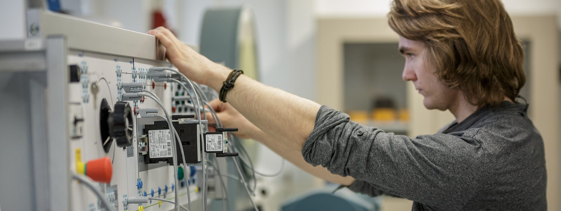 sähkö- ja automaatiotekniikkaopiskelija asentaa johtoja.