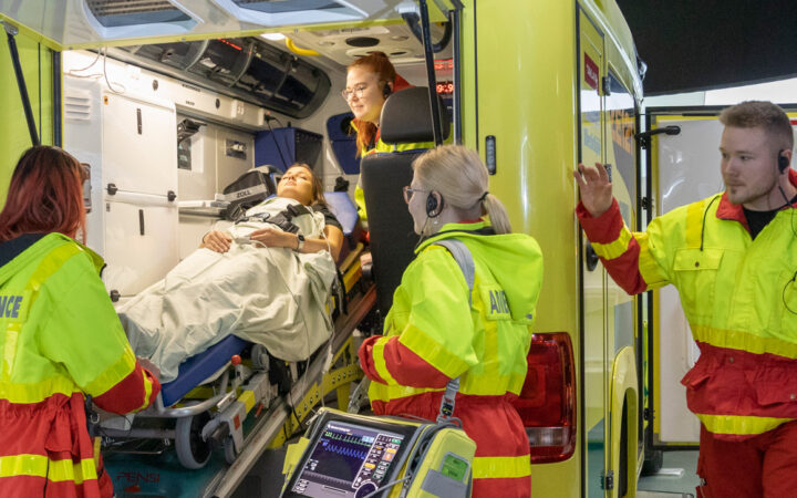 Ensihoitaja -opiskelijat harjoittelemassa ambulanssisimulaattorissa.
