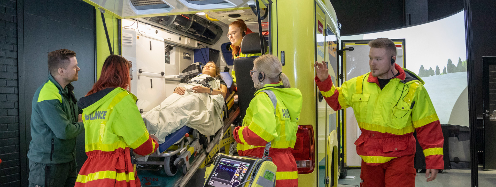 Ensihoitaja -opiskelijat harjoittelemassa ambulanssisimulaattorissa.