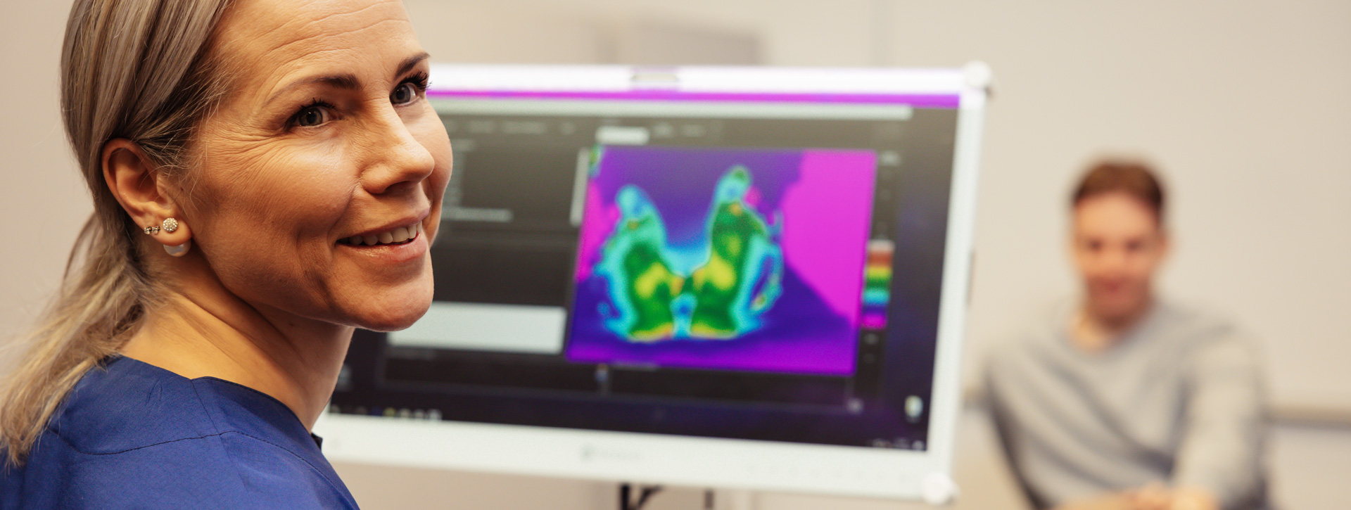 Jalkaterapeutti tutkii asiakkaan jalkoja lämpökamerateknologian avulla.