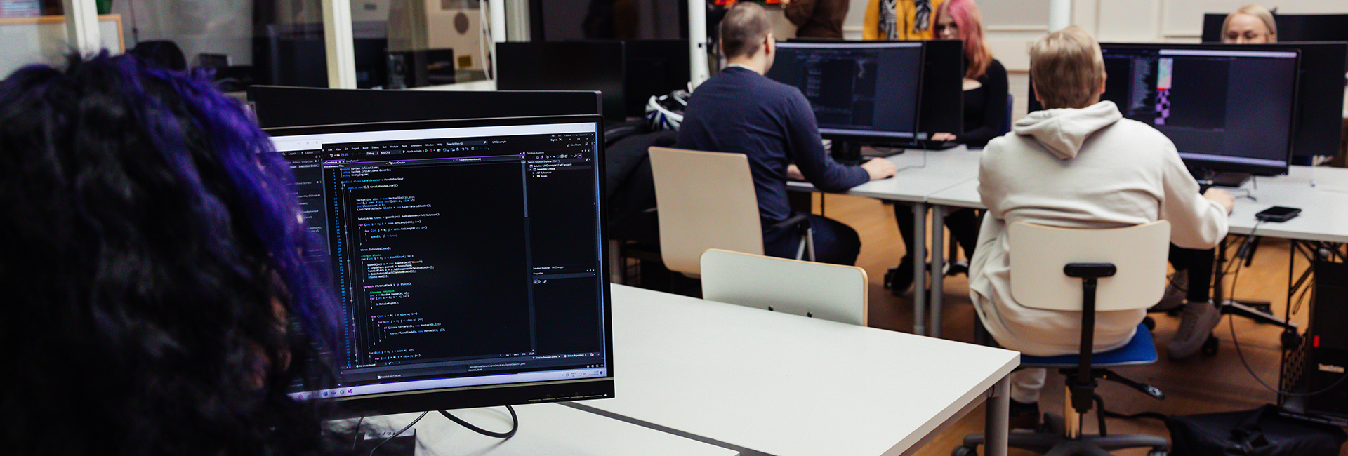 Opiskelijoita tietokoneluokassa koneiden äärellä.