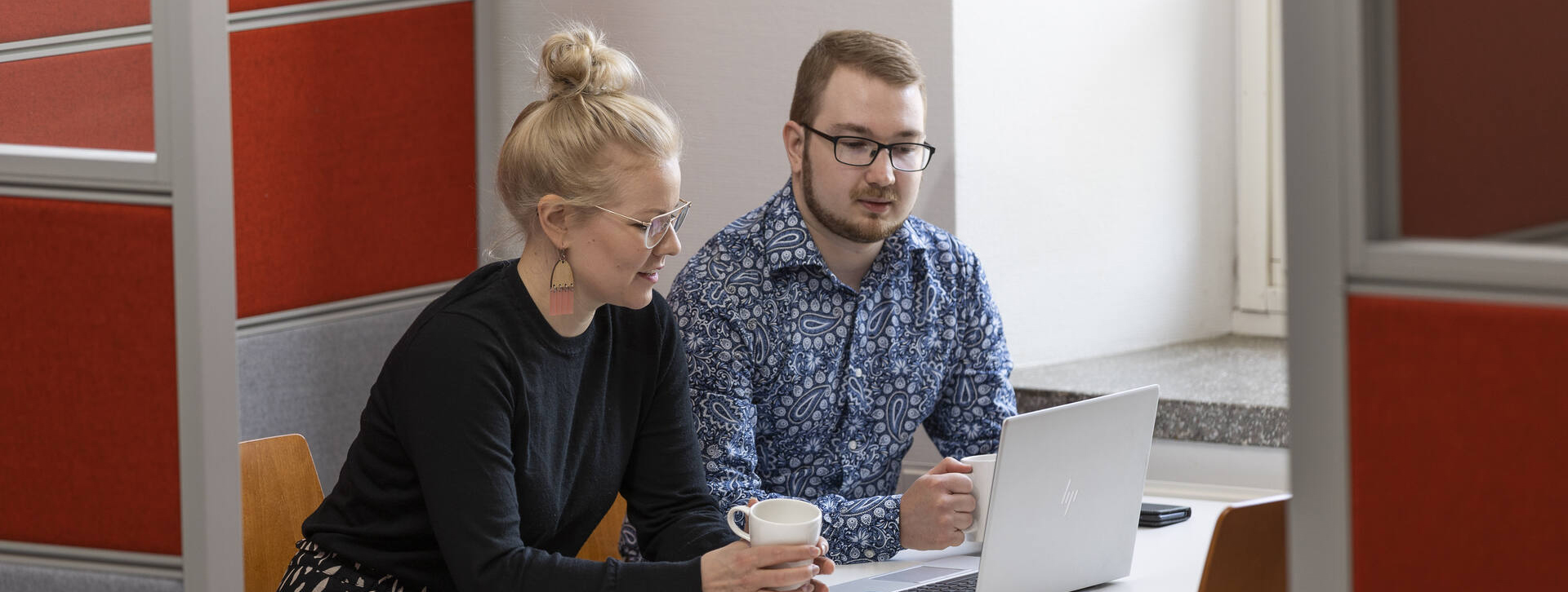Nuori nainen ja mies istuvat vierekkäin kannettavan tietokonnen äärellä.