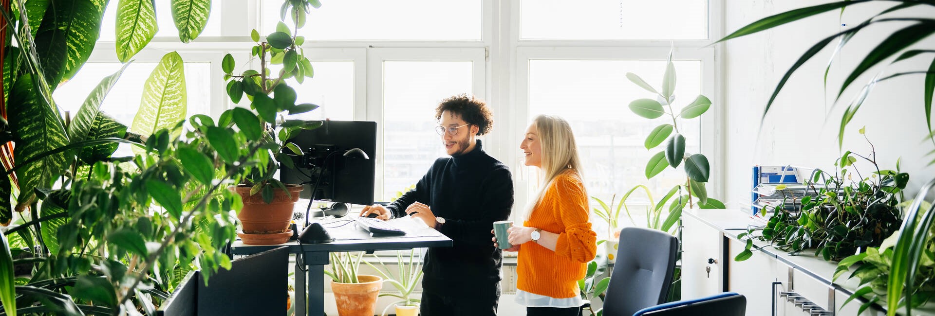 Two Colleagues Looking At Work Using Standing Desk