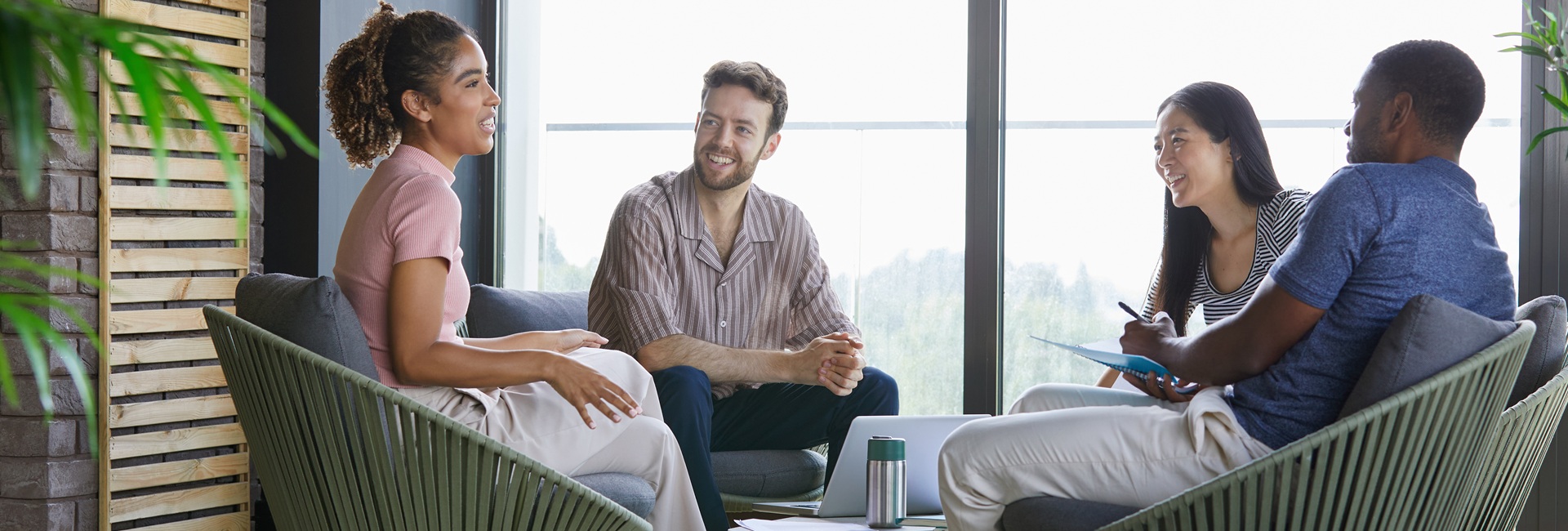 Neljä työkollegaa istumassa nojatuoleissa ja keskustelemassa. Yksi tekee muistiinpanoja.