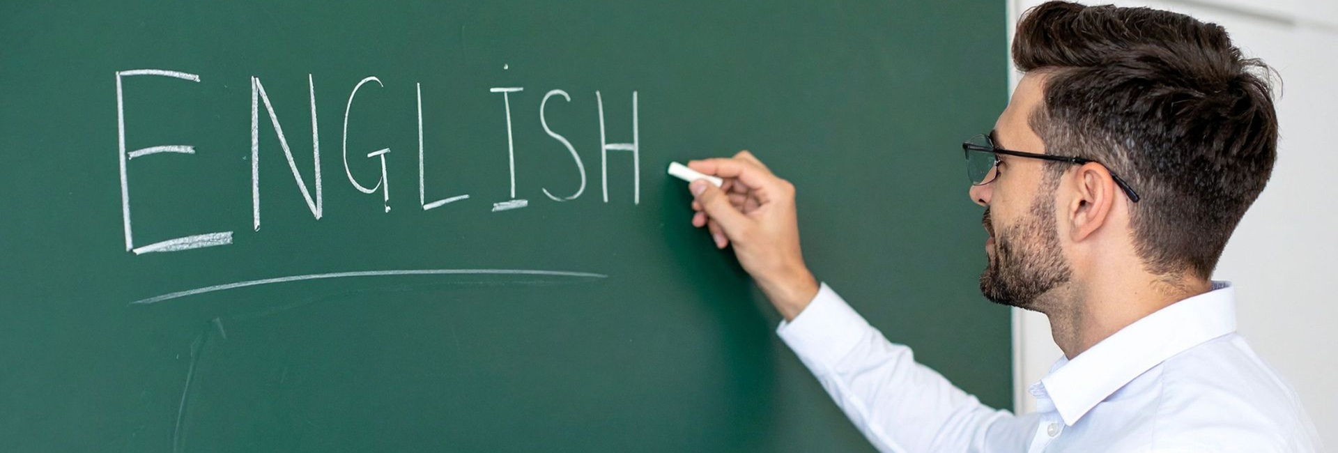 Mies kirjoittaa liitutaululle sanaa English.