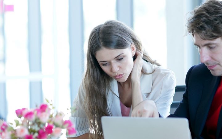 Työntekijät, nainen ja mies, tutkivat tietokoneen näyttöä.