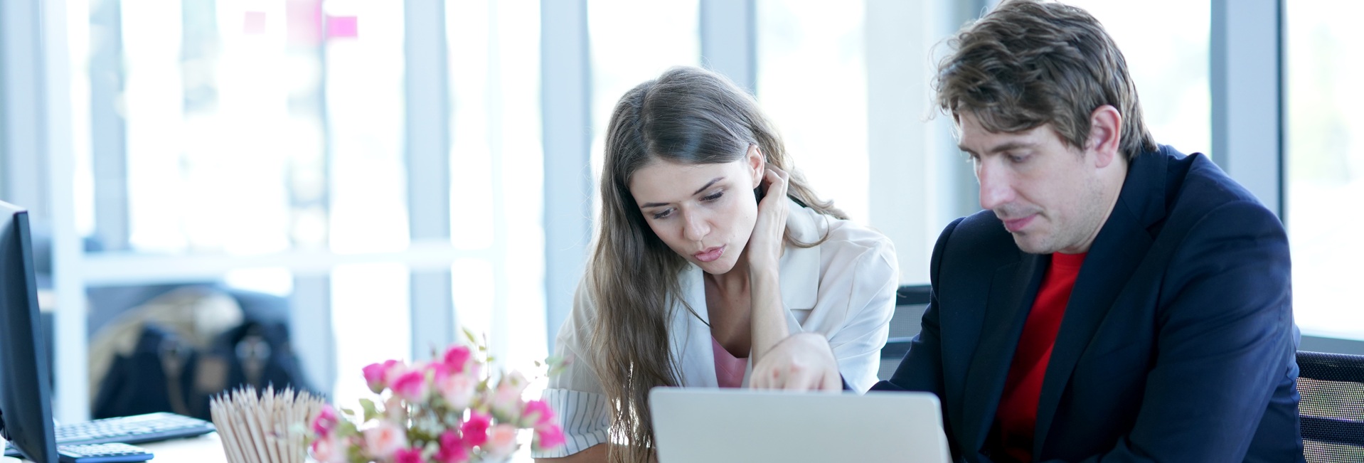 Työntekijät, nainen ja mies, tutkivat tietokoneen näyttöä.