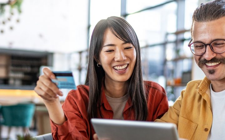 Iloinen pariskunta modernissa kahvilassa, tutkivat jotain tabletilla.