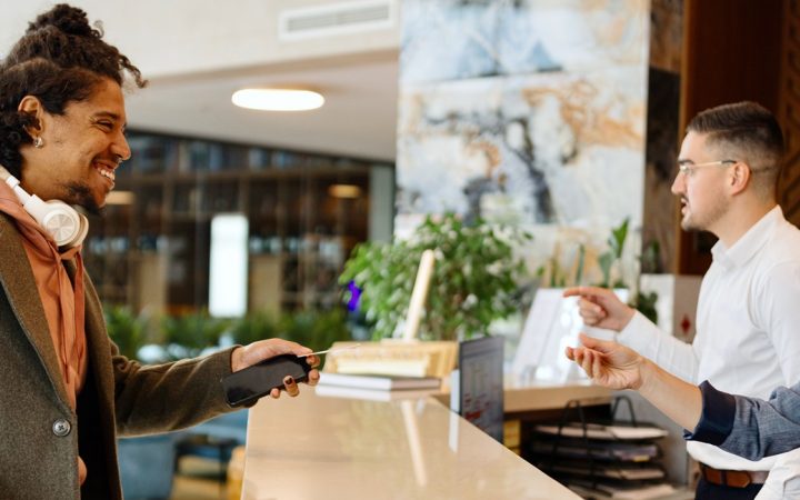 Hymyilevä latinalaisamerikkalainen liikemies kirjautuu sisään hotelliin.