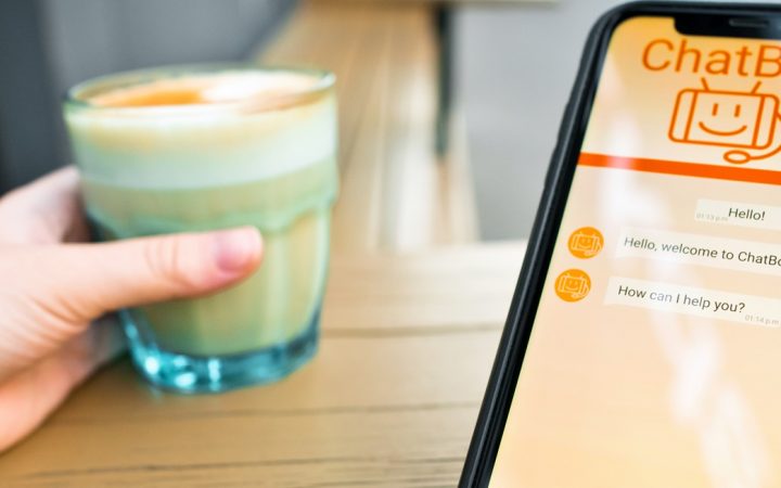 Henkilö käyttää tekoälymobiilisovellusta. Toisessa kädessä lasi maitokahvia.