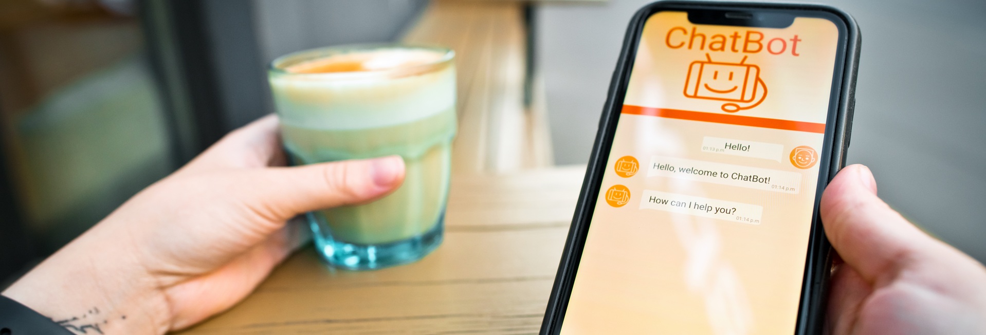 Henkilö käyttää tekoälymobiilisovellusta. Toisessa kädessä lasi maitokahvia.