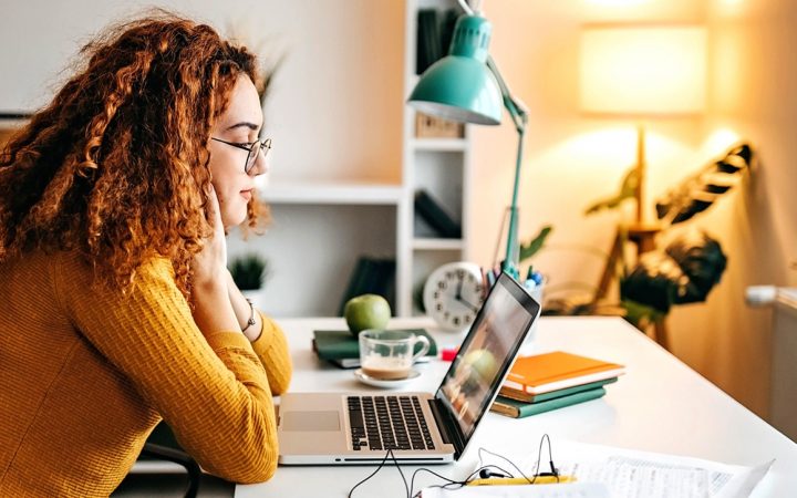 Nuori nainen opiskelemassa kannattavan tietokoneen ääressä.