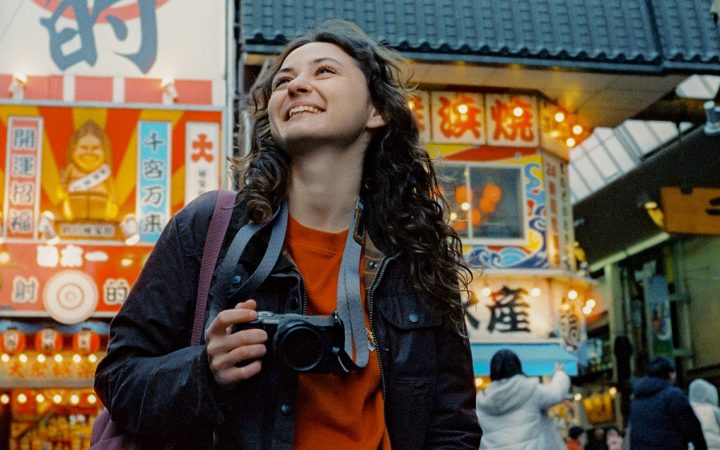 Nuori nainen kameran kanssa Osakan kaupunkimiljöössä.