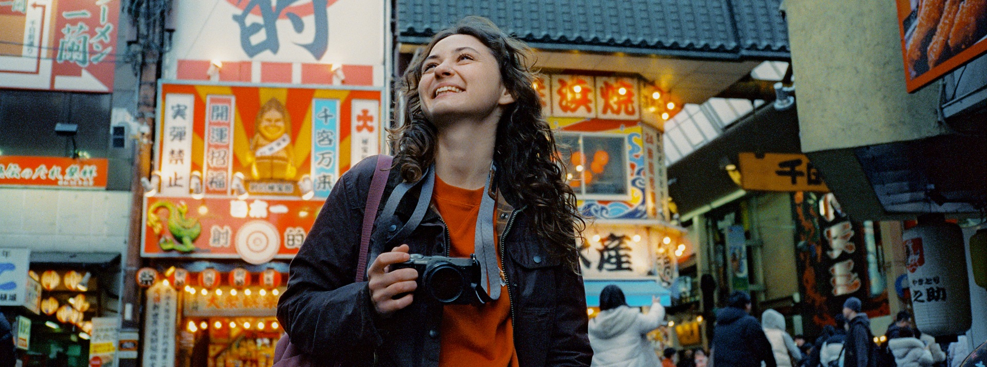 Nuori nainen kameran kanssa Osakan kaupunkimiljöössä.